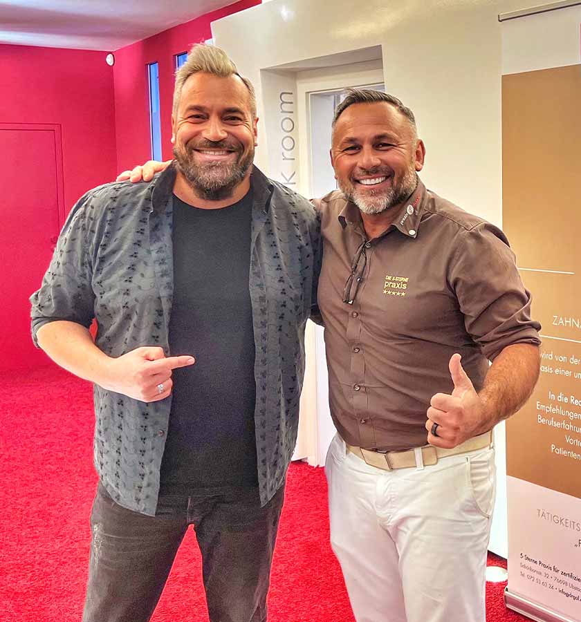 Laith Al-Deen gemeinsam mit Dr. Gal lächelnd im Eingangsbereich der 5-Sterne Praxis stehend.