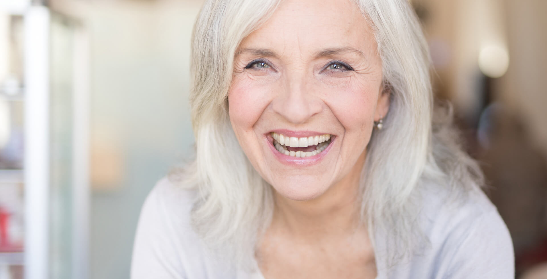 Ältere Dame, Ende 60, lächelt und denkt über schöne Zähne nach